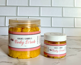 Two jars of Golden Goddess Body Scrub on a marble surface with a tiled wall background