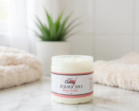 Jar of body butter with a label on a marble surface, with a plant and towel in the background.
