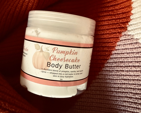 Jar of Pumpkin Cheesecake body butter on a textured brown background
