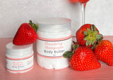 Strawberry-themed body butter jars with strawberries and a glass of strawberry champagne on a wooden surface.